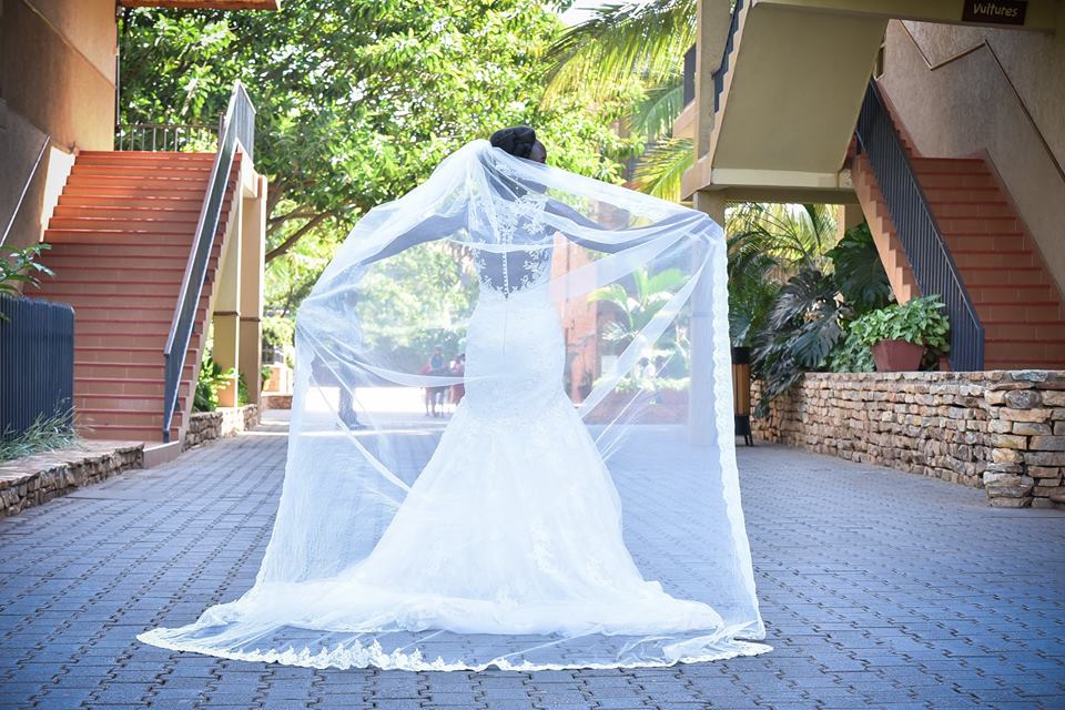 Liz shows off her long veil during a wedding photo at Speke Resort Munyonyo
