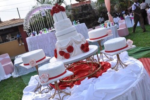 A white wedding cake decorated with red ribbons and flowers from Jari Events & Confectionary