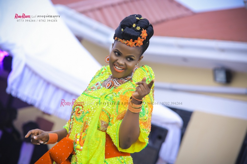 A bride dazzles in a yellow gomesi and a red sash at a customary wedding